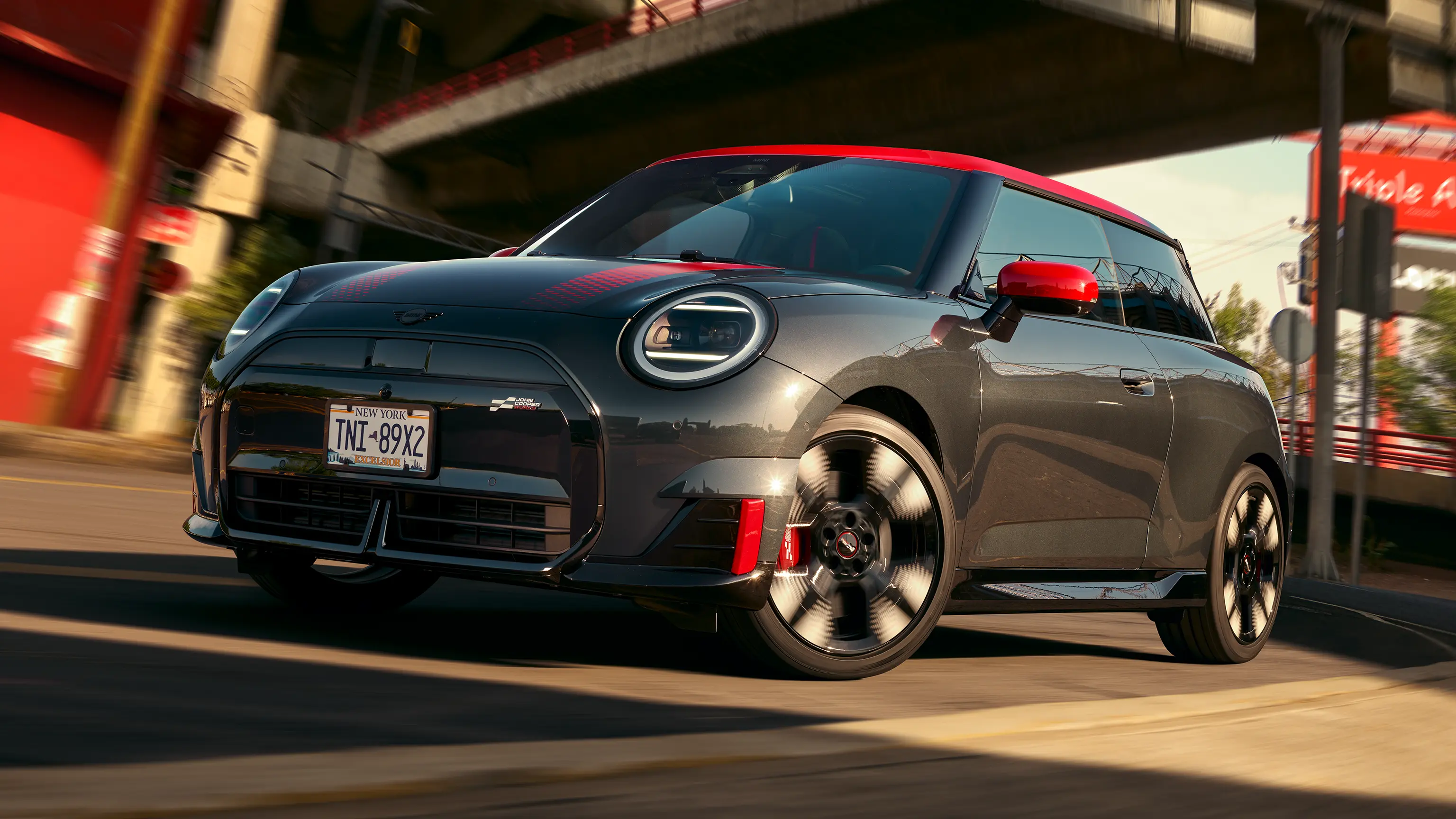 MINI John Cooper Works in Midnight Black II with Chili Red roof driving on an urban road.