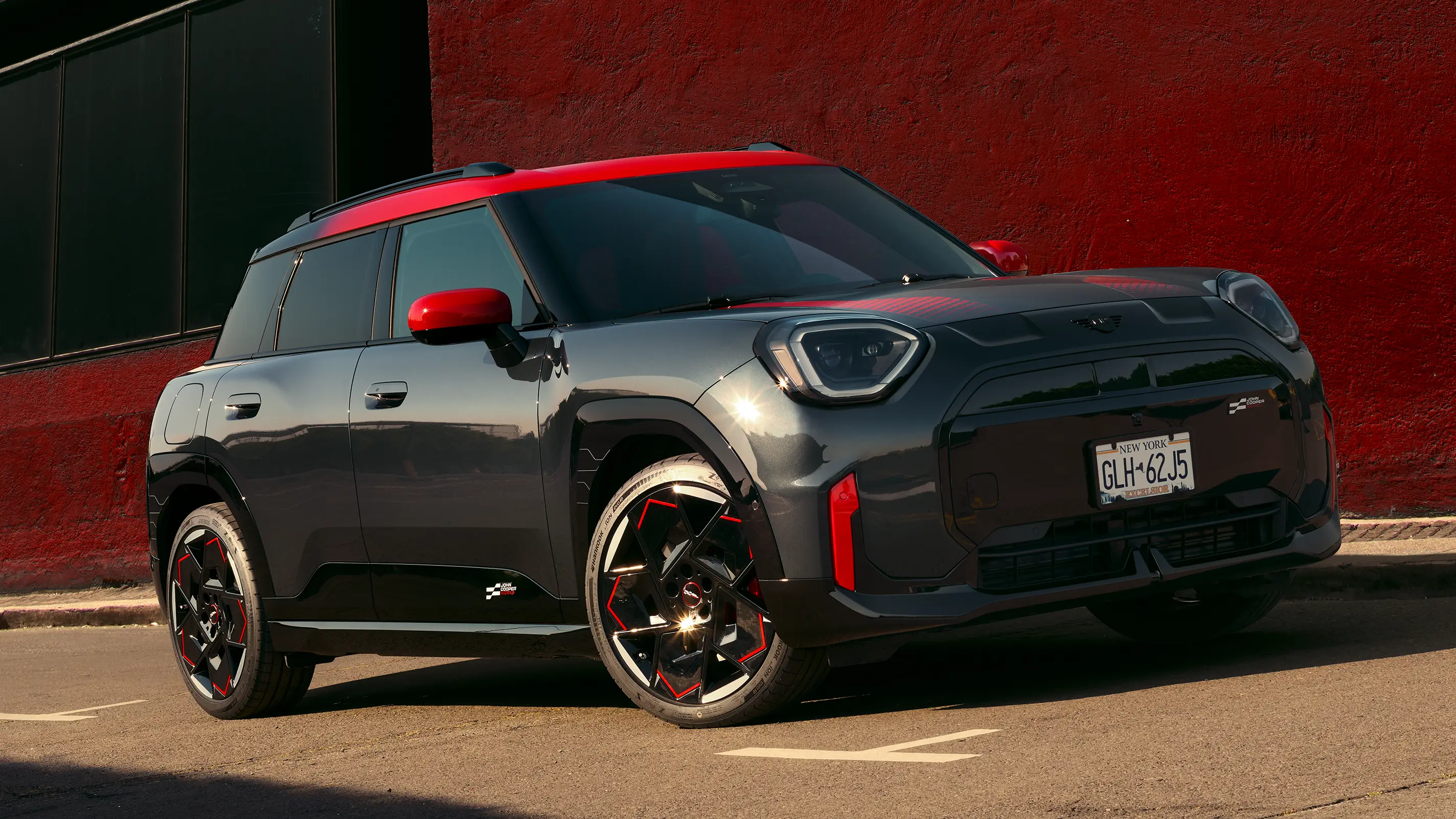 MINI Countryman John Cooper Works in Midnight Black II with Chili Red roof parked on an urban street.